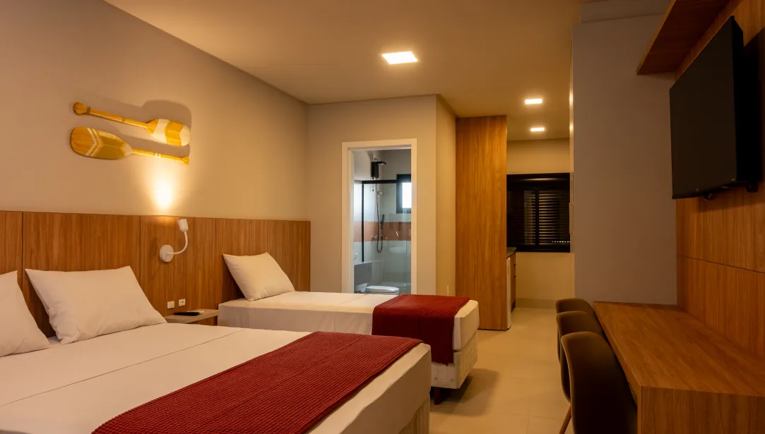 Amplo quarto, com decoração e mobiliário moderno, oferece espaço e comodidade para a sua família em um clima de praia e conforto.