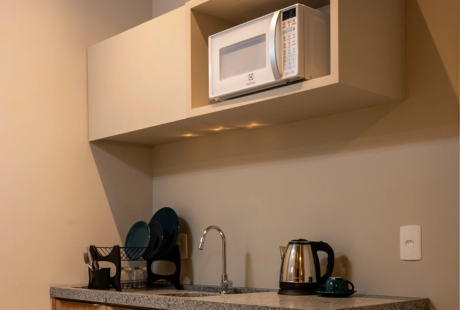 Cozinha da unidade  com micro-ondas, chaleira elétrica e utensílios completos, oferecendo praticidade durante a estada.