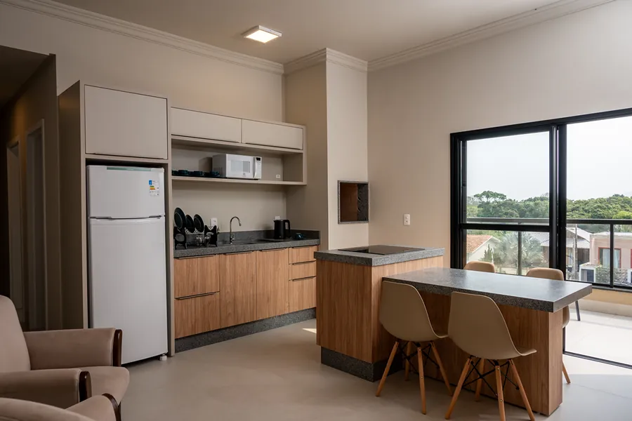Sala com cozinha integrada, incluindo geladeira, micro-ondas e área de refeições.